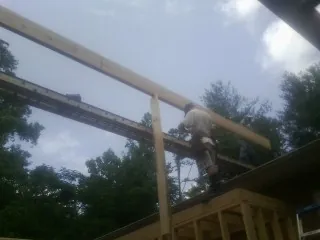 Carpenter setting a ridge beam over a new addition frame — Ice Dam Removal by Roofing Brothers in Lengby