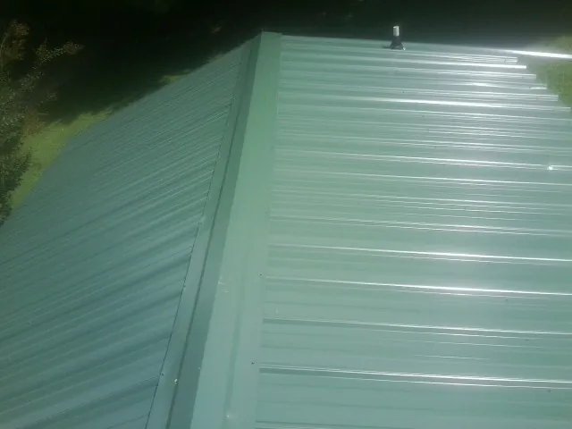 New green metal panels meeting at the ridge of a roof — Flat Roof Repair work by our crew in Lengby