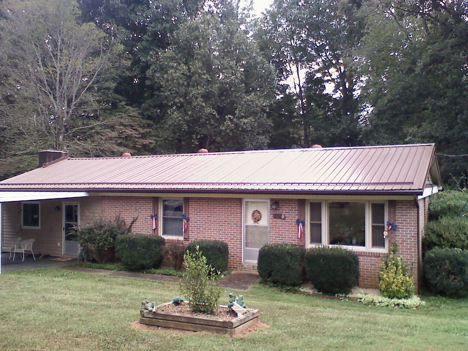 Bronze metal roof on a brick ranch home with a carport in Lengby
