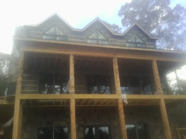 Dormers and porch framing on a large log home under construction — Roof Coating work by our crew in Lengby