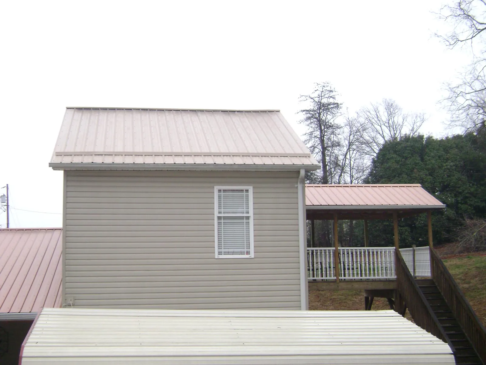 Tan metal roofs on a two story addition and attached porch, from a Roof Replacement job in Lengby