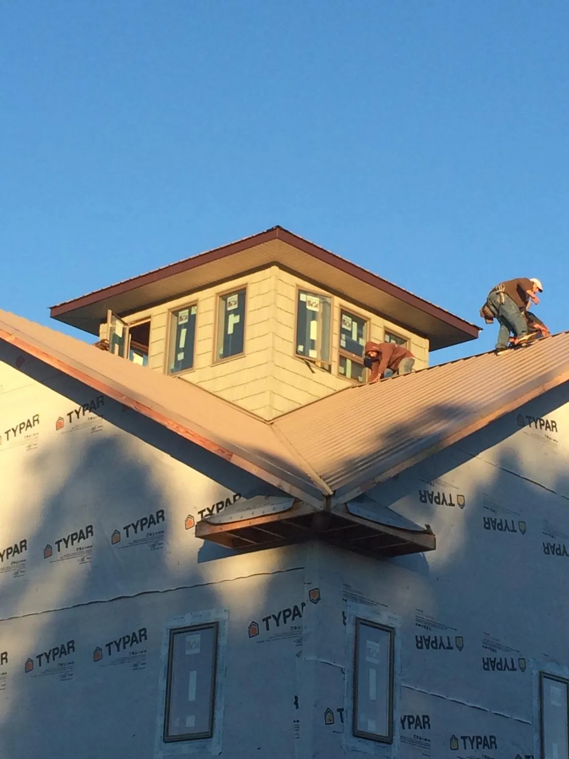 Roofers working around a rooftop cupola on a new metal roof at sunset — Roof Waterproofing in Lengby by Roofing Brothers